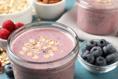 Photo of Tasty berry smoothie with oatmeal on light blue table, closeup