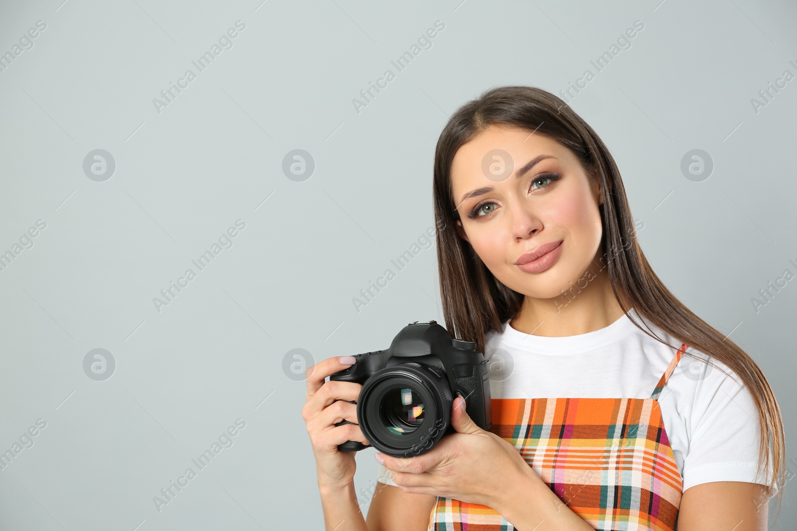 Photo of Professional photographer working on light grey background in studio. Space for text