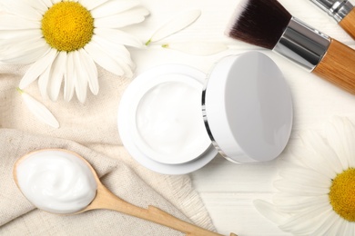 Flat lay composition with chamomiles and cream on white wooden table