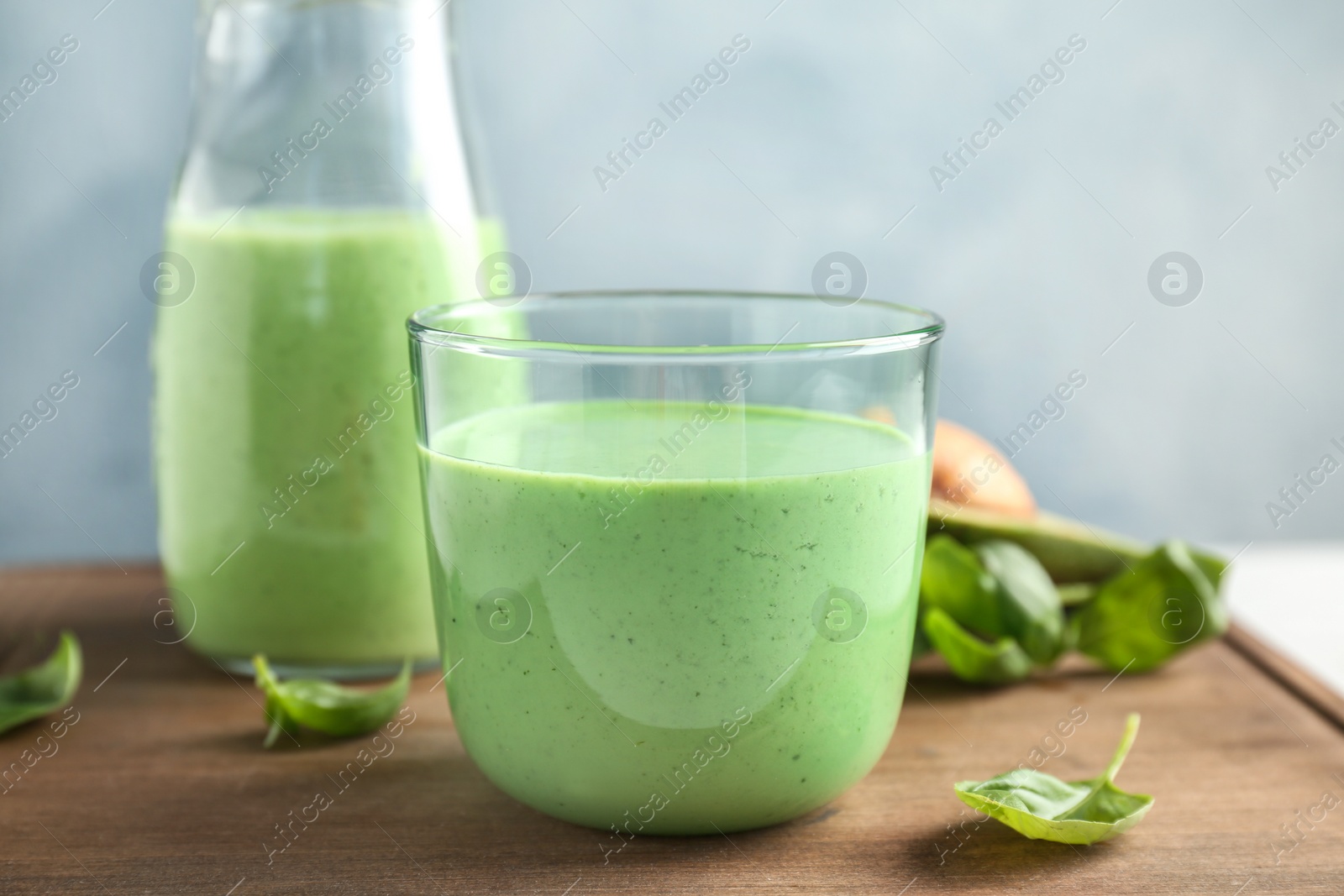 Photo of Glassware with healthy detox smoothie and spinach on table