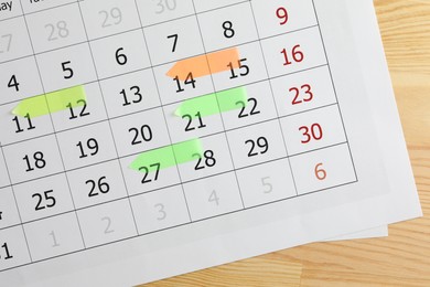 Photo of Timetable. Calendar page with colorful sticky notes on wooden table, top view