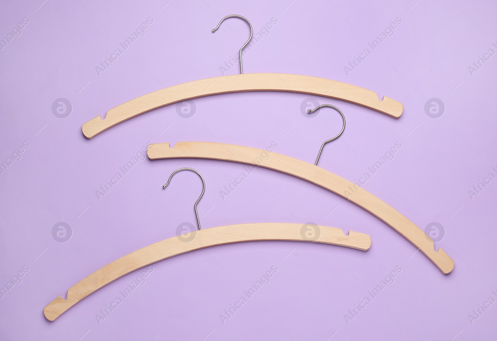 Photo of Empty hangers on lilac background, flat lay