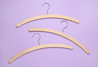 Photo of Empty hangers on lilac background, flat lay