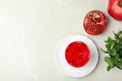 Photo of Flat lay composition with red jelly in bowl and pomegranate on light table. Space for text