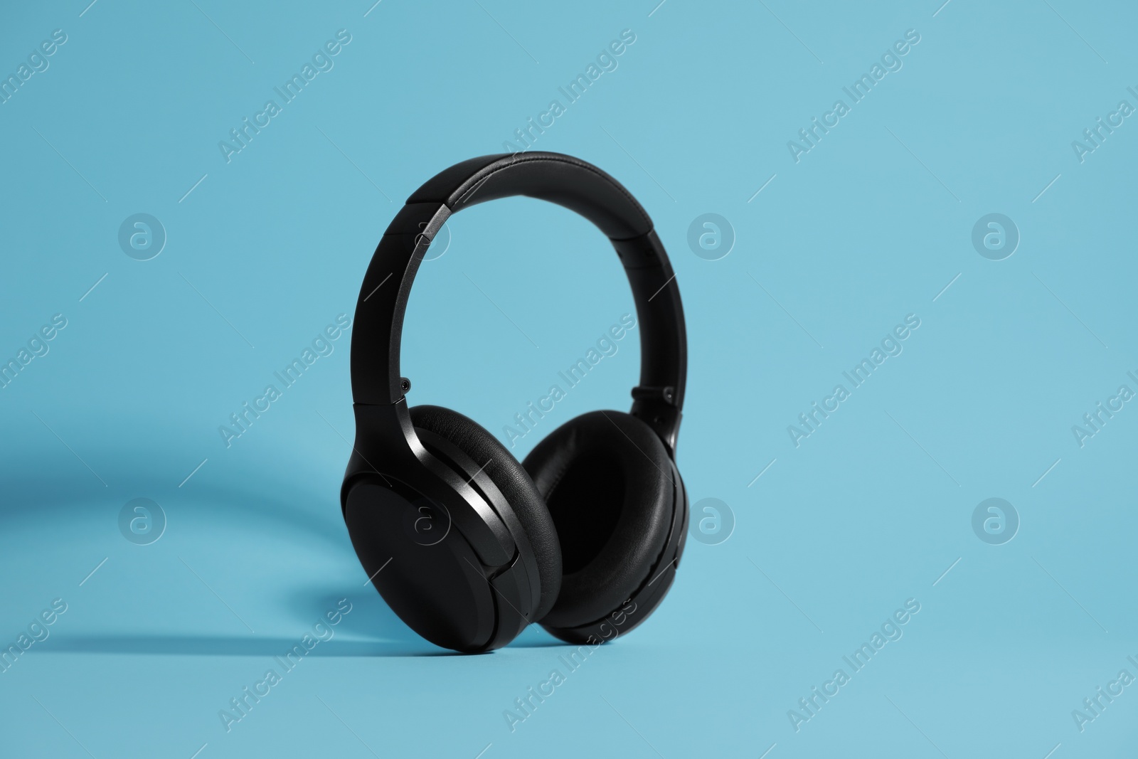 Photo of Modern wireless headphones on light blue background