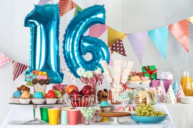 Photo of Dessert table in room decorated with blue balloons for 16 year birthday party