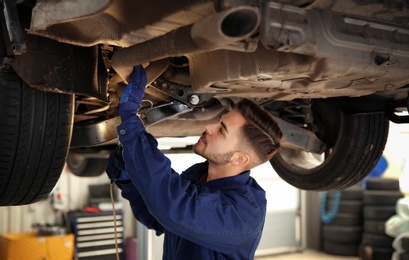 Technician checking modern car at automobile repair shop