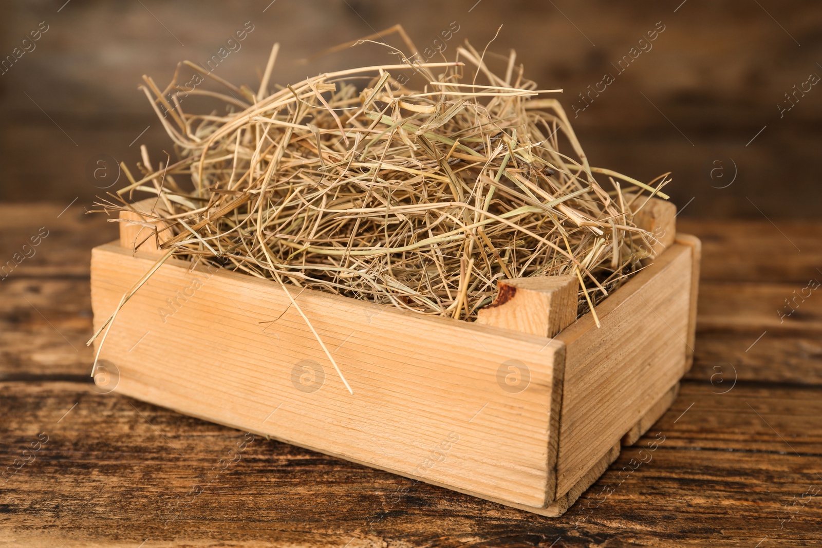 Photo of Dried hay in crate on wooden table