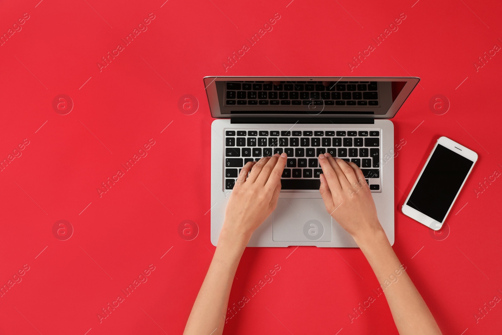 Photo of Woman using modern laptop at color table, top view