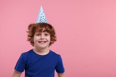 Happy little boy in party hat on pink background. Space for text