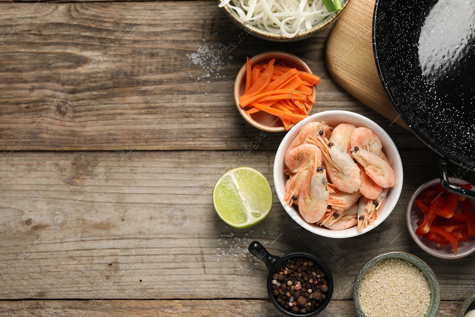 Photo of Flat lay composition with black wok, spices and products on wooden table. Space for text