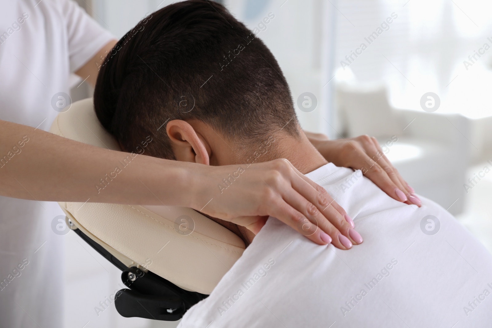 Photo of Man receiving massage in modern chair indoors, closeup