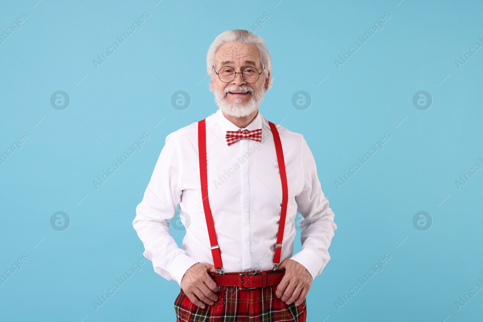 Photo of Portrait of stylish grandpa with glasses and bowtie on light blue background