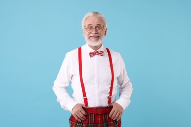 Portrait of stylish grandpa with glasses and bowtie on light blue background