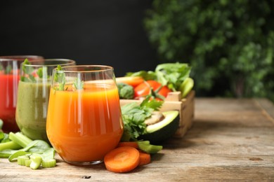 Delicious vegetable juices and fresh ingredients on wooden table. Space for text