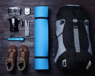 Photo of Flat lay composition with backpack and other different camping equipment for tourism on wooden background