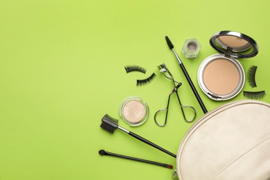 Flat lay composition with eyelash curler, makeup products and accessories on light green background. Space for text