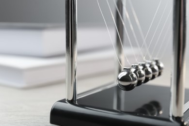 Photo of Newton's cradle on wooden table, closeup. Physics law of energy conservation