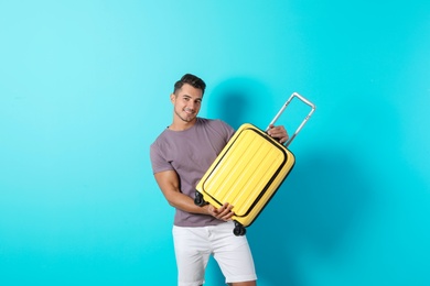 Photo of Young man with suitcase on color background