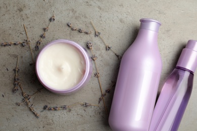 Photo of Set of hair care cosmetic products and dry lavender flowers on grey stone table, flat lay