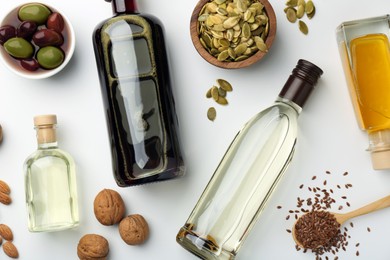 Vegetable fats. Different oils in glass bottles and ingredients on white table, flat lay
