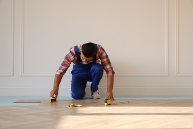 Professional worker installing new parquet flooring indoors