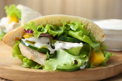Delicious pita sandwiches with chicken breast and vegetables on wooden table, closeup
