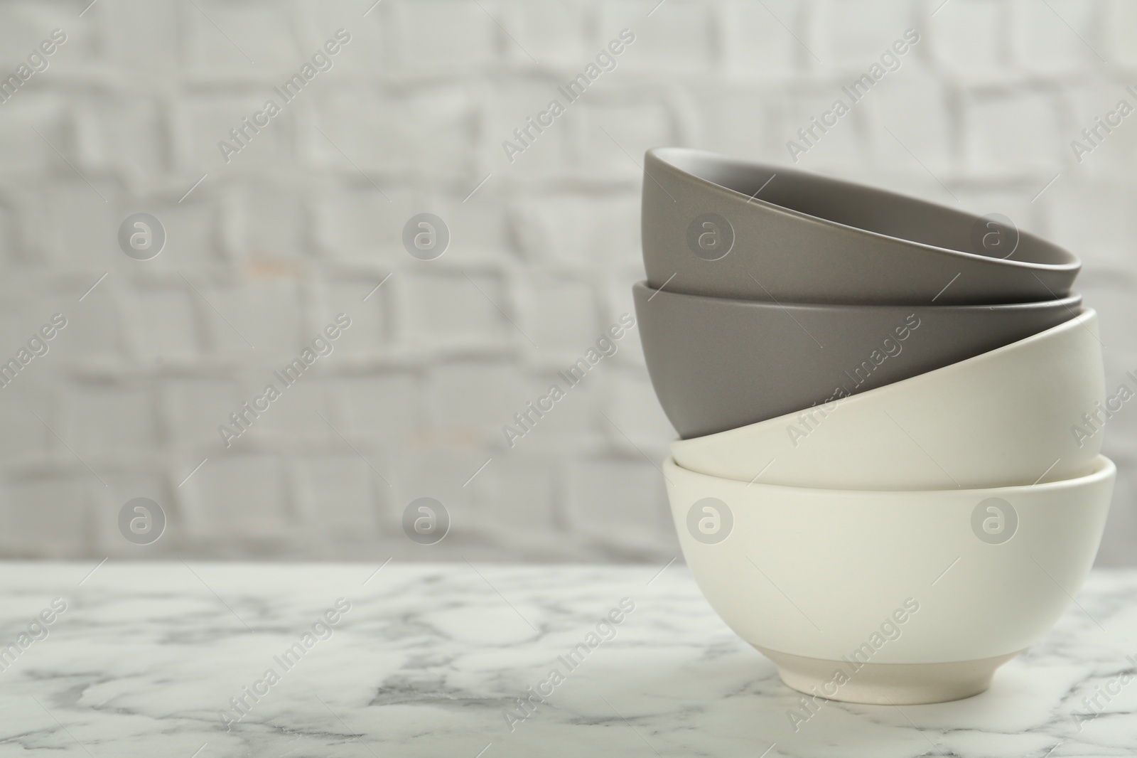 Photo of Stylish empty ceramic bowls on white marble table, space for text. Cooking utensils