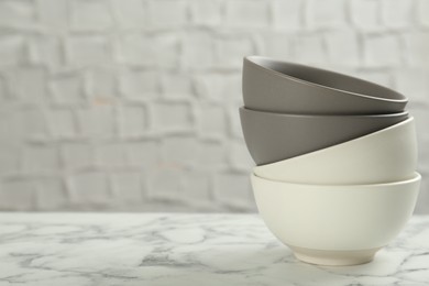 Stylish empty ceramic bowls on white marble table, space for text. Cooking utensils