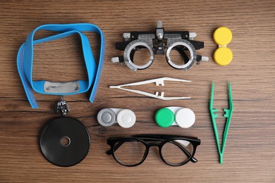Photo of Different ophthalmologist tools on wooden background, flat lay