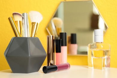 Photo of Lipsticks and holder with other makeup products on dressing table, space for text