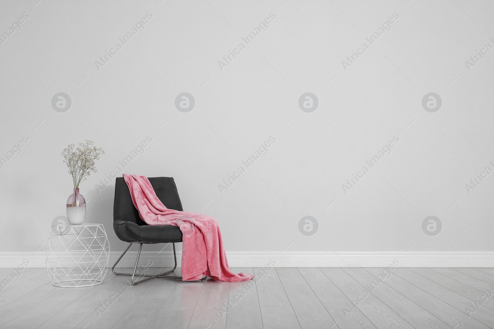 Photo of Stylish room interior with comfortable chair and plaid near white wall. Space for text