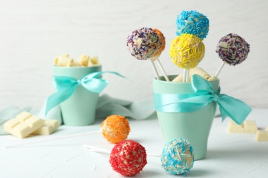 Cup with bow and yummy colorful cake pops on table. Space for text