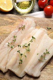 Board with raw cod fish, microgreens and products on grey table, flat lay