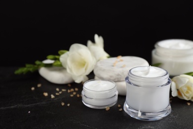 Beautiful spa composition with cosmetic products and flowers on black table, closeup