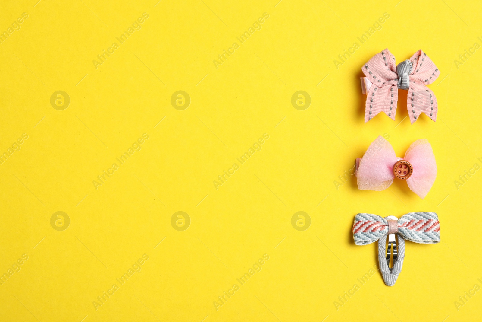 Photo of Cute hair clips on yellow background, flat lay. Space for text