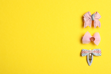 Cute hair clips on yellow background, flat lay. Space for text