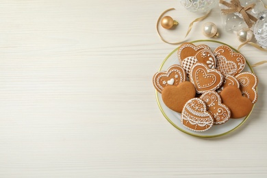 Photo of Tasty heart shaped gingerbread cookies and Christmas decor on white wooden table, flat lay. Space for text