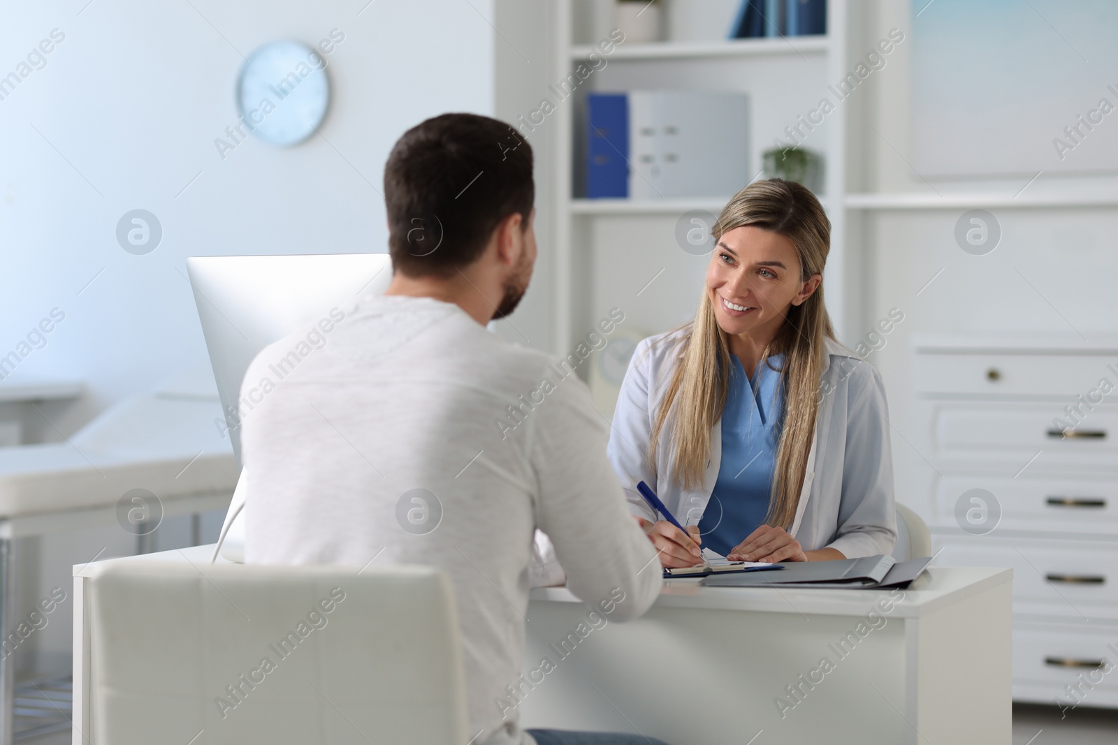 Photo of Professional doctor working with patient at white table in hospital