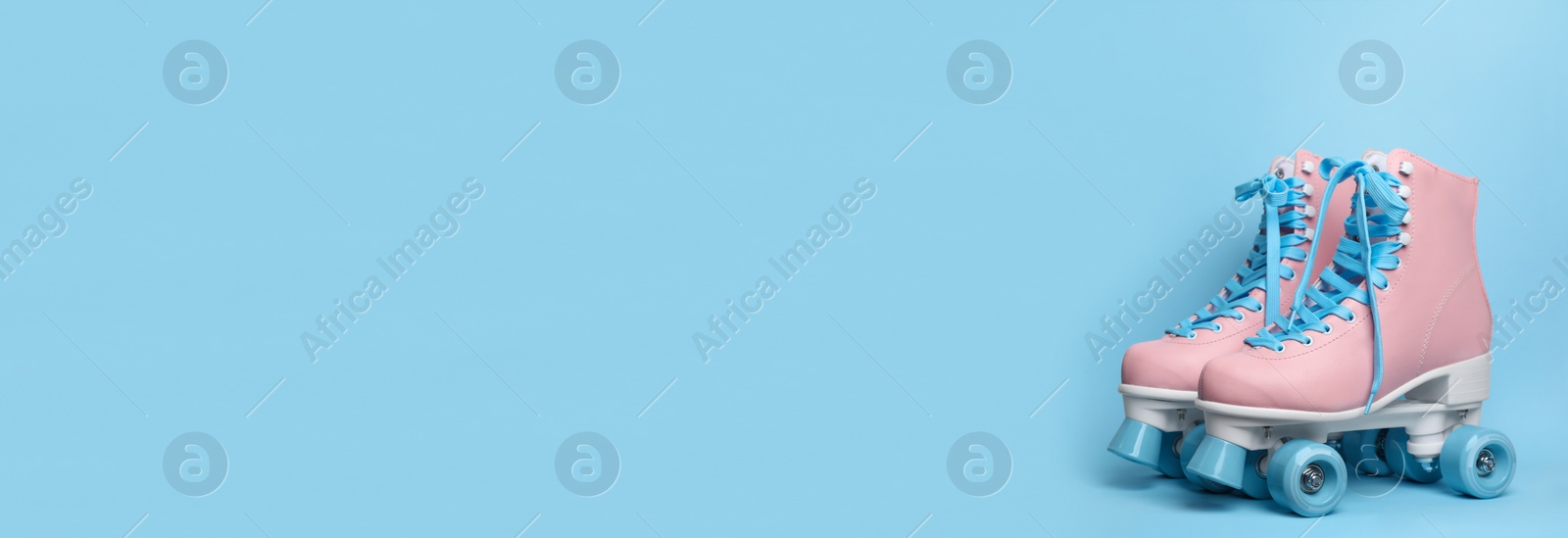 Image of Pair of stylish quad roller skates on light blue background, space for text. Banner design