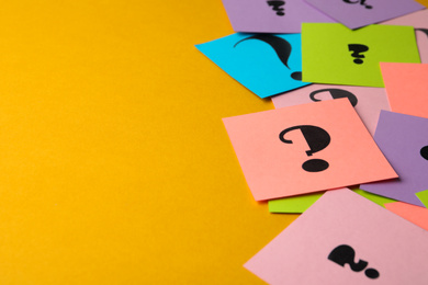 Paper cards with question marks on yellow background, closeup. Space for text
