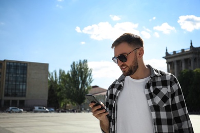 Young man with smartphone on city street