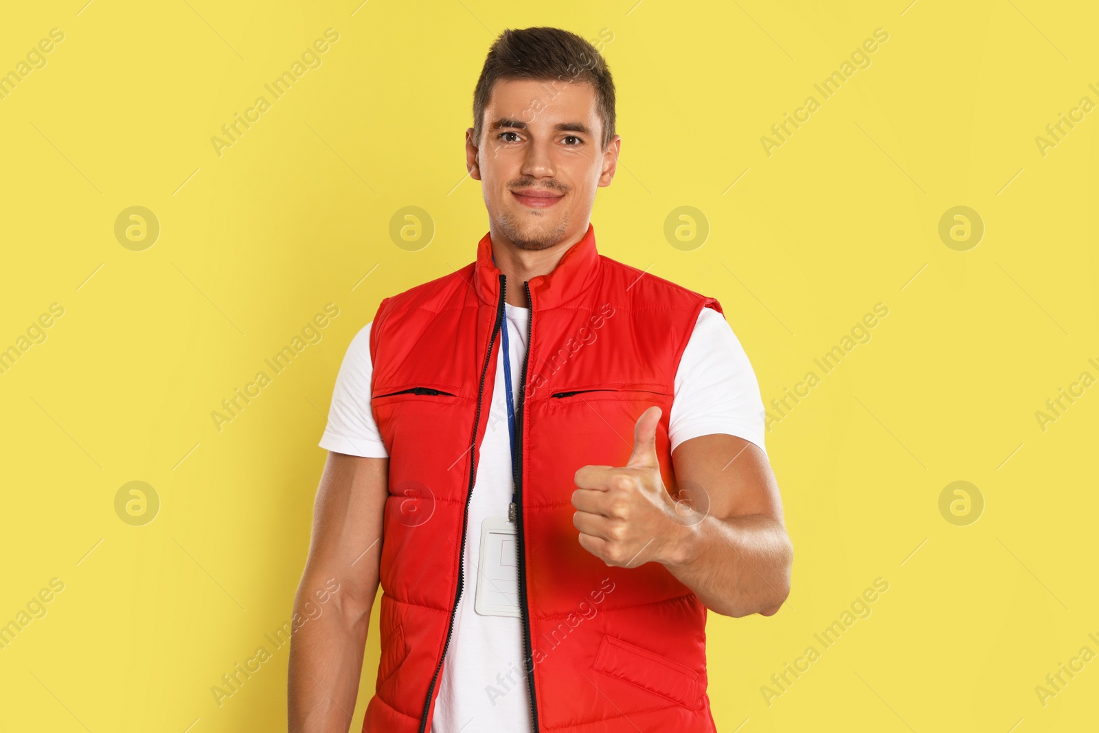 Photo of Portrait of happy young courier on yellow background