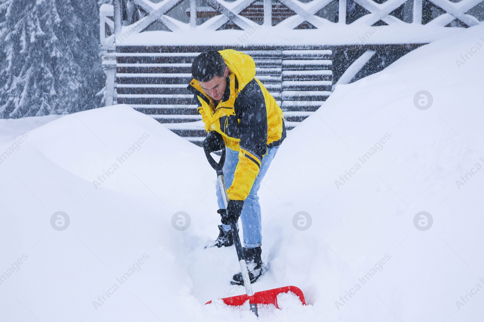 Photo of Man cleaning snow with shovel near house