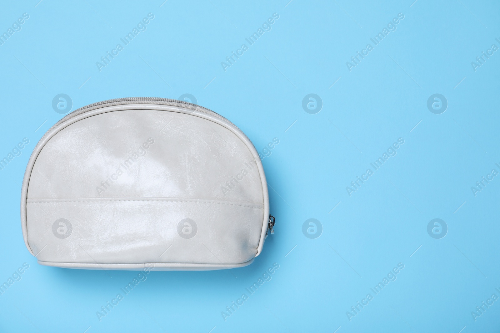 Photo of White leather cosmetic bag on light blue background, top view. Space for text