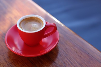 Photo of Cup of hot aromatic coffee on table in outdoor cafe. Space for text