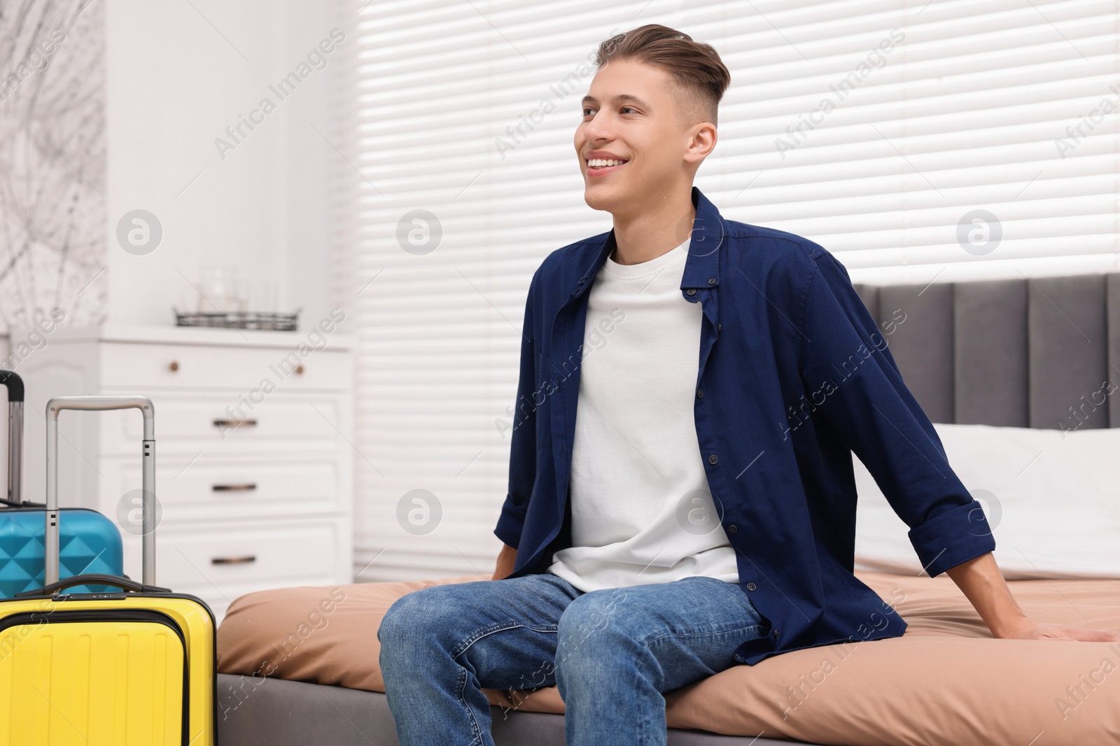 Photo of Smiling guest relaxing on bed in stylish hotel room