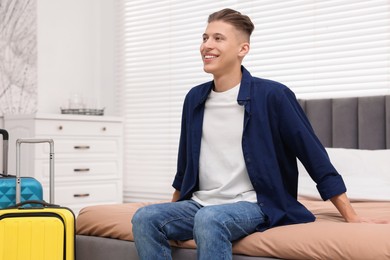 Photo of Smiling guest relaxing on bed in stylish hotel room