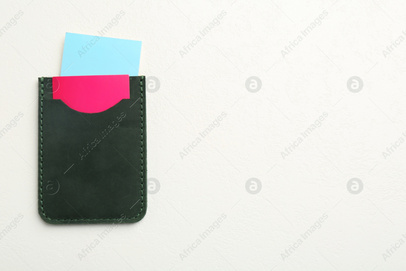 Photo of Leather business card holder with colorful cards on white table, top view. Space for text