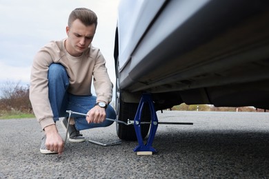 Young man changing tire of car on roadside